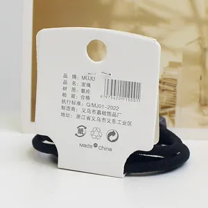 Detailed view of the black elastic hair tie with white brand card packaging, high stretch material.