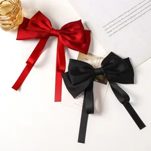 Close-up detail shot of elegant satin bow hair clips with long drapes in red and black colors.
