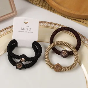 Close-up of braided hair ties set with rhinestone flower beads on display card and plate.