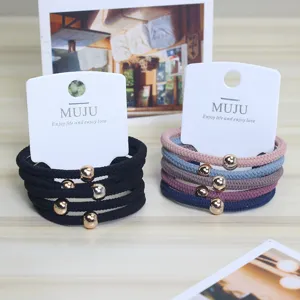 Detail view of 5-pack elastic hair ties with gold beads on display cards, multi-color nylon.