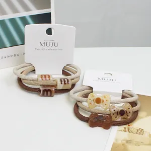 Detail shot of 3-pack hair ties with elastic twill bands, marble cloud and bow resin ornaments.