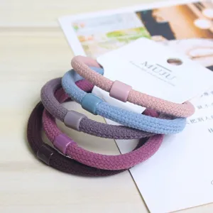 Close-up detail of colorful elastic hair ties with decorative tubes mounted on a display card.