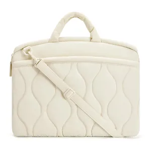 Nahaufnahme einer gepolsterten gesteppten Laptoptasche in Creme mit Griffen und Schultergurt.