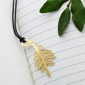 Metal leaf bookmark with cord on notebook background, creative stationery gift item.