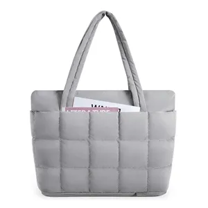 Close-up of the grey quilted puffer tote bag highlighting its padded grid pattern and front pocket.