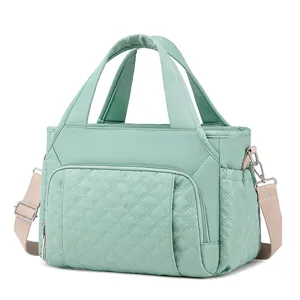 Quilted green lunch bag detail view, thermal insulated handbag with sturdy handles and adjustable strap.