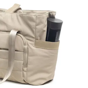 Détail de sac cabas matelassé avec poche latérale et sangle en tissu durable.