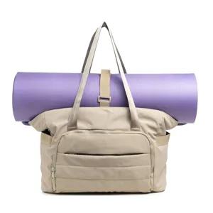 Vue détaillée du sac cabas beige en toile avec un tapis de yoga violet fixé.