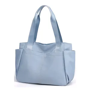 Detail view of the light blue lightweight nylon tote bag showing dual fabric handles and exterior pockets.