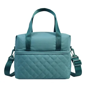 Detail view of the teal insulated lunch bag showing quilted bottom and sturdy shoulder strap.