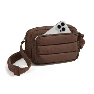Brown quilted puffer crossbody bag with adjustable strap and front zipper pocket detail.