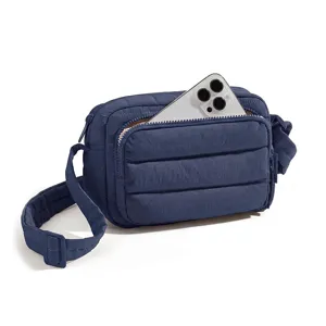 Dark blue quilted crossbody bag featuring front zipper pocket and adjustable strap detail.