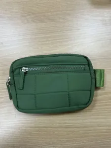 Dark green nylon quilted detail view showing texture, zipper, and side webbing loop.