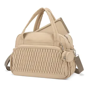 Close-up detail of quilted beige baby diaper bag showcasing texture, handles and side pouch.