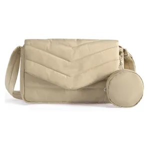Detail view of quilted beige crossbody bag with flap, adjustable strap and round pouch.