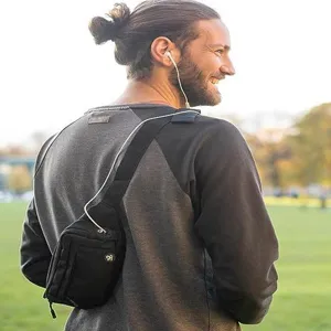 Λεπτομέρεια lifestyle σε εξωτερικό χώρο από μαύρη τσάντα στήθους στον ώμο στο πάρκο.
