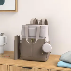 Detailed view of multi-functional diaper backpack in beige and khaki, styled on a wooden desk.