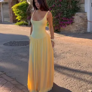 Detailed view of the yellow sleeveless spliced pleated long dress in a scenic outdoor setting.