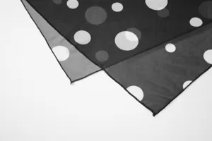Close-up detail of the black sheer mesh fabric featuring stylish white polka dots.