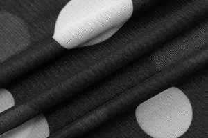 Close-up detail of black and white polka dot mesh fabric texture, soft and delicate.