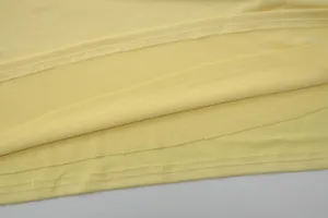 Detailed view of women's yellow dress fabric, showing fine stitching and smooth texture.
