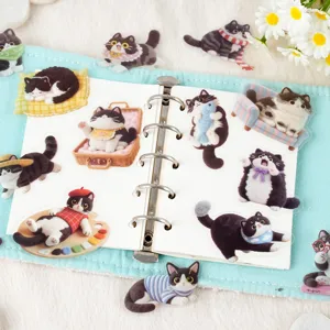 Close-up of cute felt black and white cat PET stickers displayed in a binder notebook.