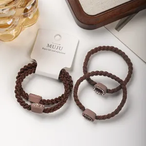 Detail close-up of brown braided hair ties with rhinestone charms on display card.