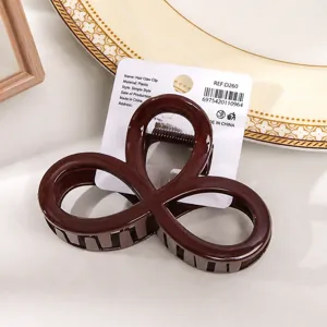 Vue gros plan détaillée d'une pince à cheveux géométrique rouge foncé avec étiquette carton.