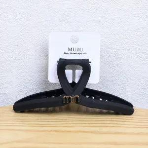 Matte black claw clip detail shot, elegant hollow geometric hair accessory with card packaging.