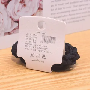 Detailed close-up of a black braided hair tie with a backing card, showing texture and design.