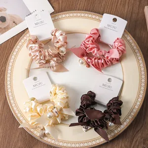 Silk satin hair scrunchies with pearls and ribbons, elegant daily hair accessories detail view.