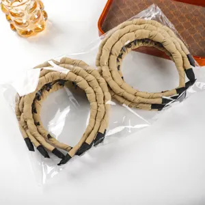 Vista dettagliata di cerchietti per capelli in tessuto beige con denti, imbottiti.