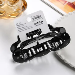 Black and white polka dot hair claw clip close-up detail, stylish daily hair accessory for women.
