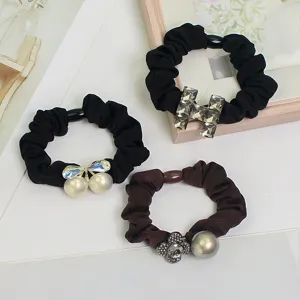 Detail view of stylish crystal hair scrunchies with luxury H motif and pearls for women.