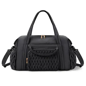 Black quilted travel duffel bag detail view, showing front braided pocket and side pockets.