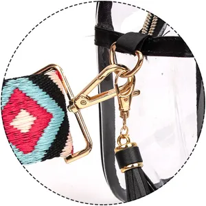 Dettaglio della minuteria della borsa in PVC, tracolla ricamata e ciondolo con nappa.