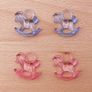 Close-up detail of clear acrylic rocking horse pendants in blue and pink for baby shower.