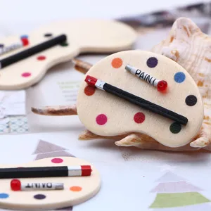 Détail de palette en bois miniature avec petits pinceaux et tubes de peinture pour maison de poupée.