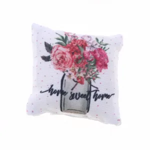 Detailopname van miniatuur poppenhuis bankkussen met bloemenprint en leuke tekst erop.