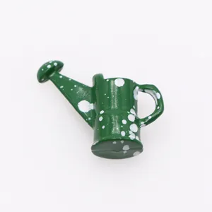 Annaffiatoio verde miniatura con macchie bianche, ideale per decorare case delle bambole.