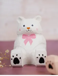 Close-up detail of the cute carved wooden bear phone stand with pink bow and paw prints.