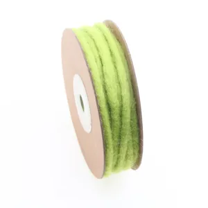 Close-up detail of light green wool felt cord on spool for DIY crafts and holiday decor.