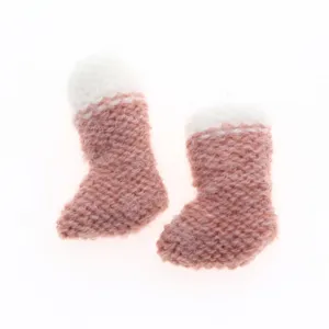 Miniature knitted wool boots detail, pink and white tiny winter shoes close up for decoration.