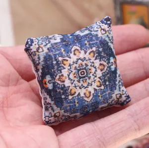Miniature dollhouse throw pillow detail showing traditional bohemian rug pattern on soft fabric.