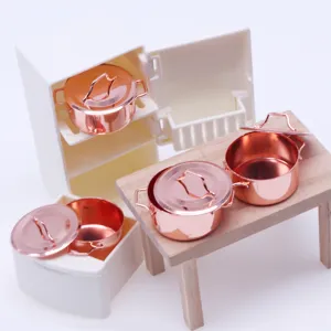 Miniature dollhouse kitchen metal copper-colored soup pots with tiny wooden table and fridge.