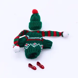 Detailed shot of miniature doll knitted sweater, matching hat, scarf, and cute red shoes.