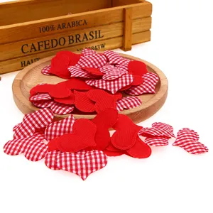 Primer plano de corazones de tela roja y de cuadros para decoración de bodas y manualidades.