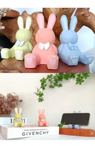 Détail de support de téléphone lapin géométrique avec joli nœud 3D et pattes sur bureau en bois.