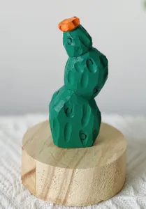 Close-up detail of a handmade wooden cactus figurine with orange flower on a round wooden base.