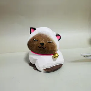 Handmade wooden carved kitten figurine detail shot, cute cat ornament with bell decor.